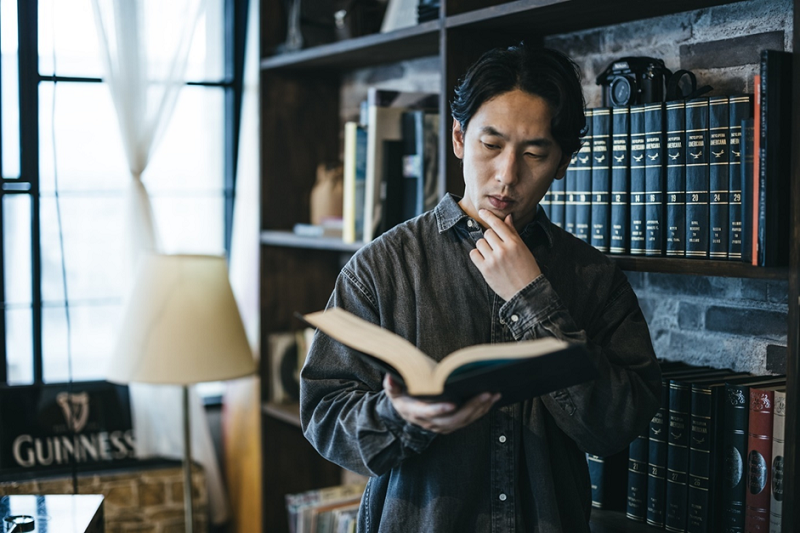 本で調べものをする人物